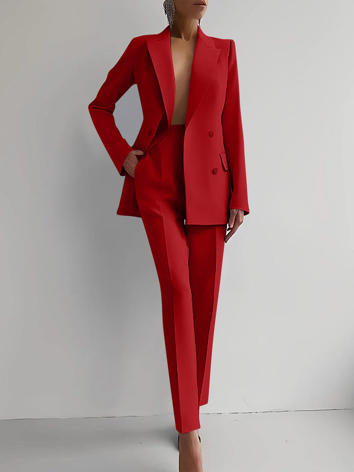 Woman wearing a bold red double-breasted peaked lapel blazer and slim straight-leg trousers suit set