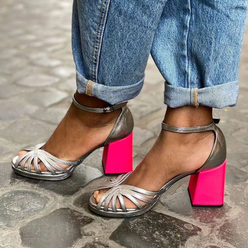 Shiny silver open-toe block heel sandal with ankle buckle strap, side view on plain background
