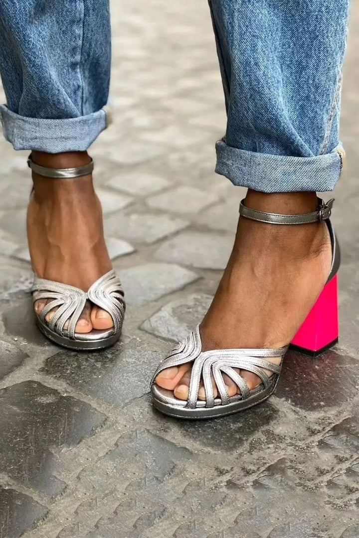 Close-up of glossy silver block heel buckle sandal showing open toe and heel detail