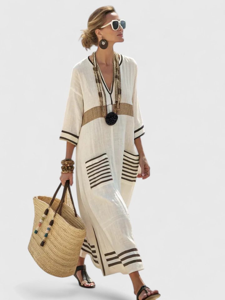Woman wearing the Serena beige and black stripe V-neck kaftan maxi dress with contrast trim patch pockets