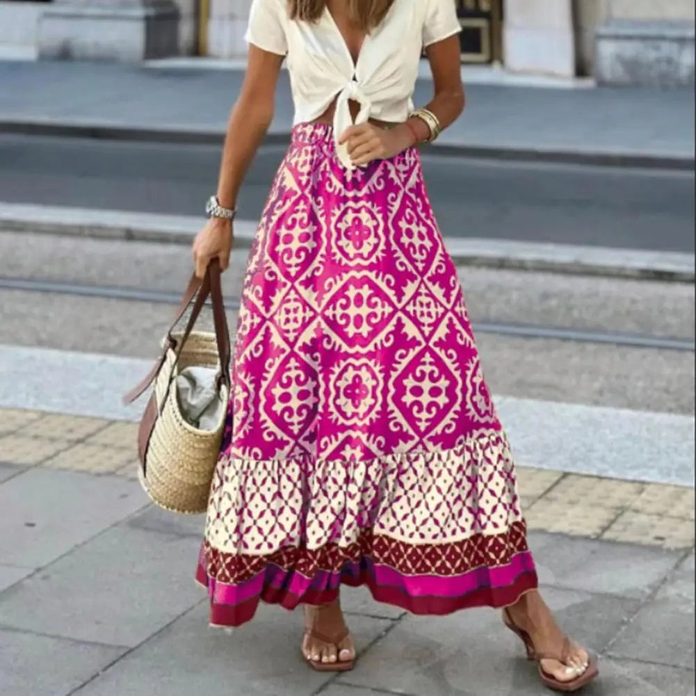 Woman wearing a pink high-waist boho maxi skirt with geometric tile print and ruffle hem, styled with a white top and sandals