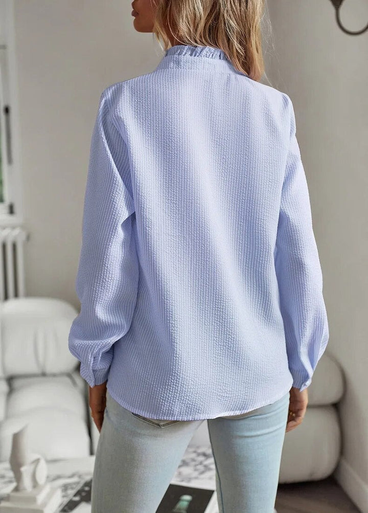Front view of the Sheri pleated long-sleeve blouse styled with trousers in a neutral setting
