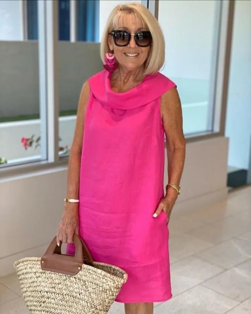 Woman wearing a lightweight sleeveless summer dress with a wide flattering neckline in a soft pink color