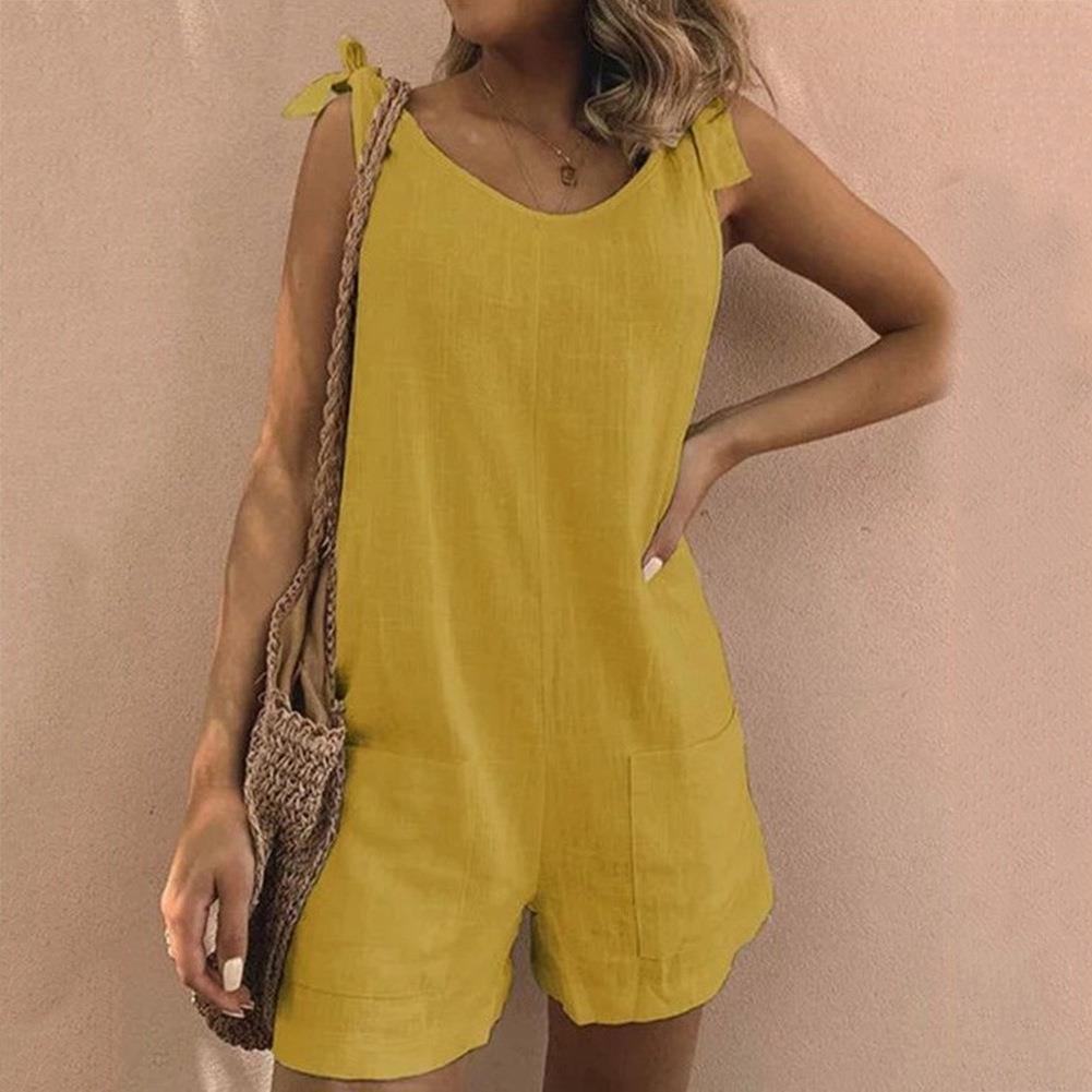 Full-length view of a bow strap pocket playsuit in orange, worn outdoors in warm sunlight