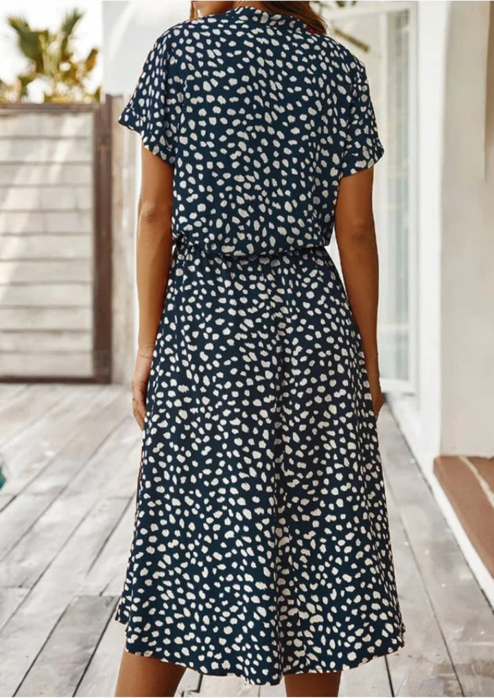 Lifestyle shot of model in white spotted print midi dress in an outdoor setting