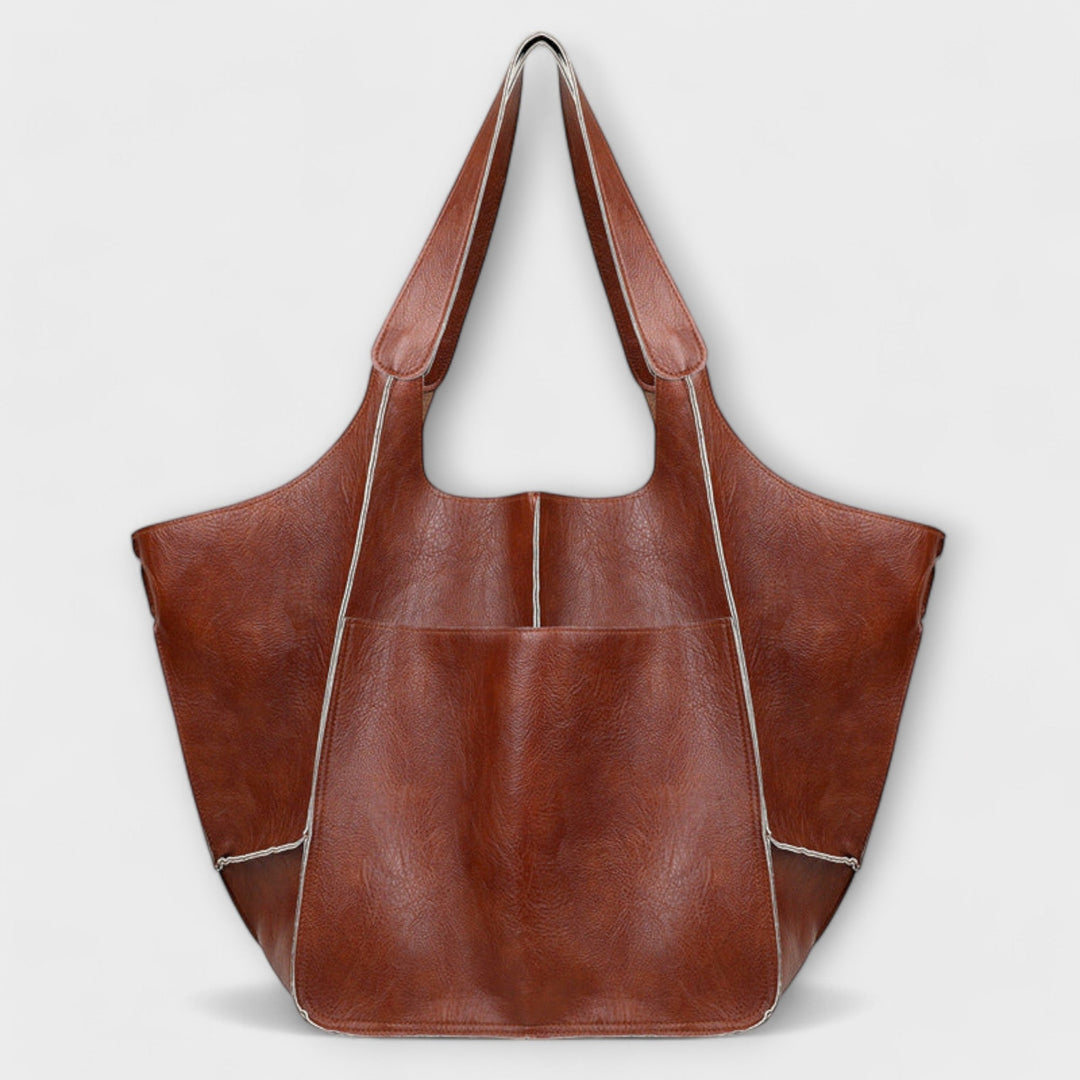 Sigrid Everyday Bag in yellow held by carry handles against a bright background