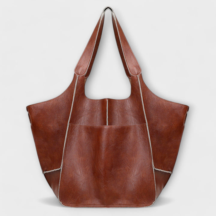 Sigrid Everyday Bag in yellow held by carry handles against a bright background