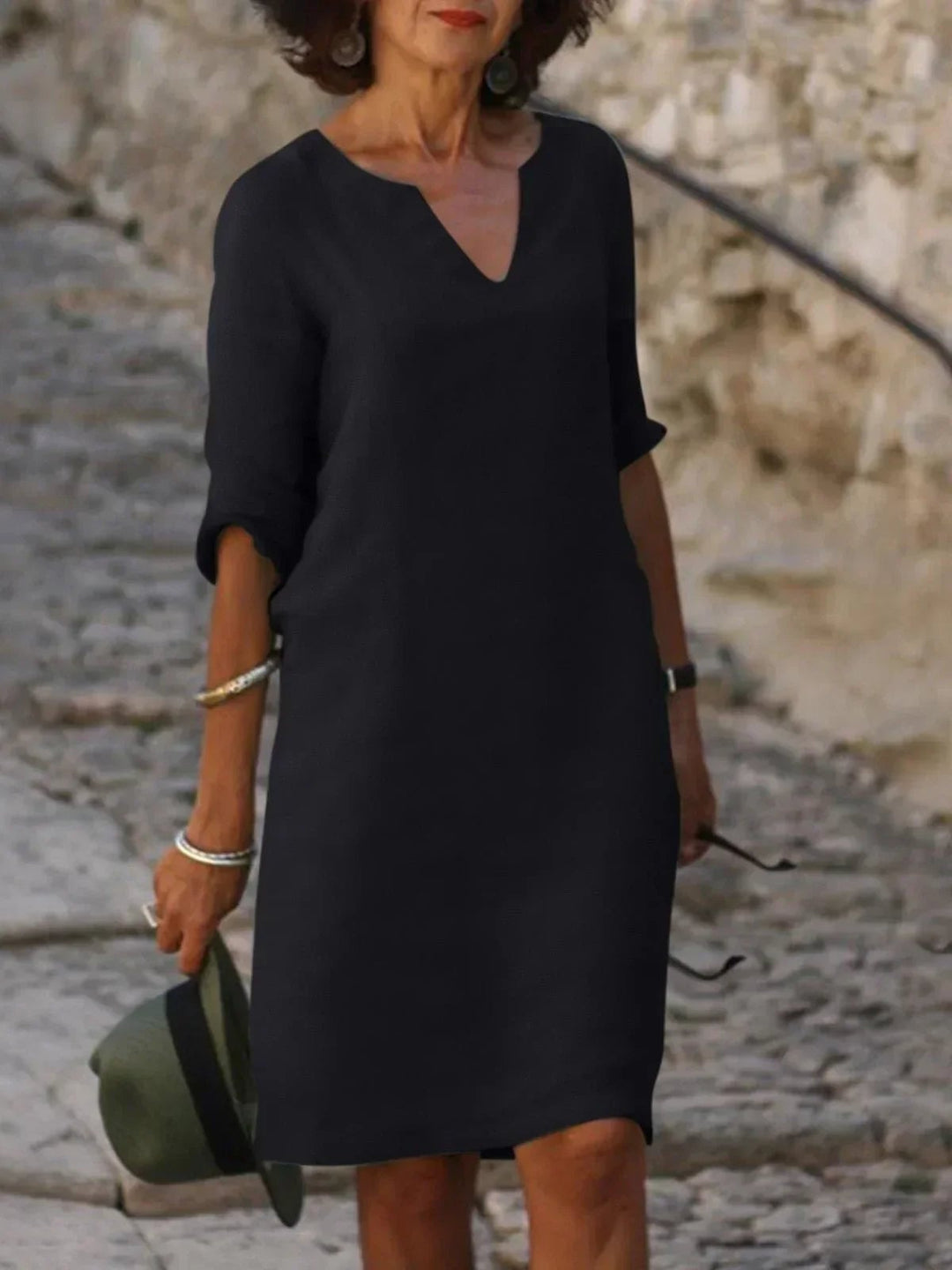 Woman wearing a black elegant V-neck dress with pleated details and flattering belly coverage