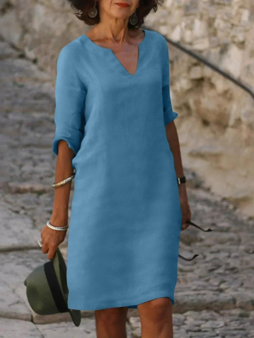 Lifestyle shot of a woman in a black V-neck dress accessorized with heels and jewelry