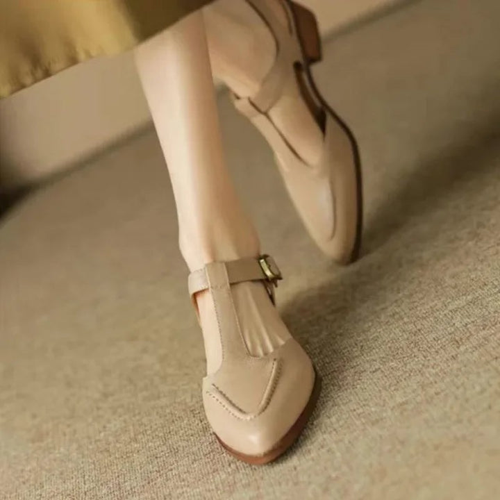 Close-up of gold-tone buckle hardware on the Sloane T-strap flat in light brown