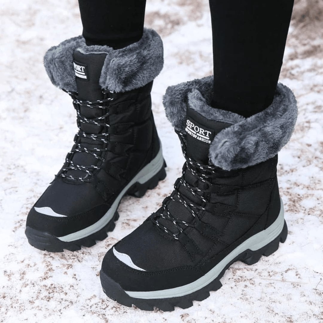 Woman wearing warm insulated winter boots in beige on a snowy street, styled with jeans and a winter coat