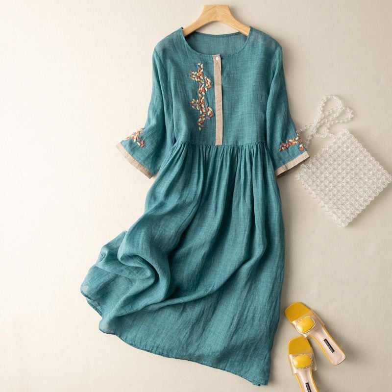 Woman wearing a relaxed floral embroidered midi dress with half sleeves and a soft round neckline in a green pattern colorway