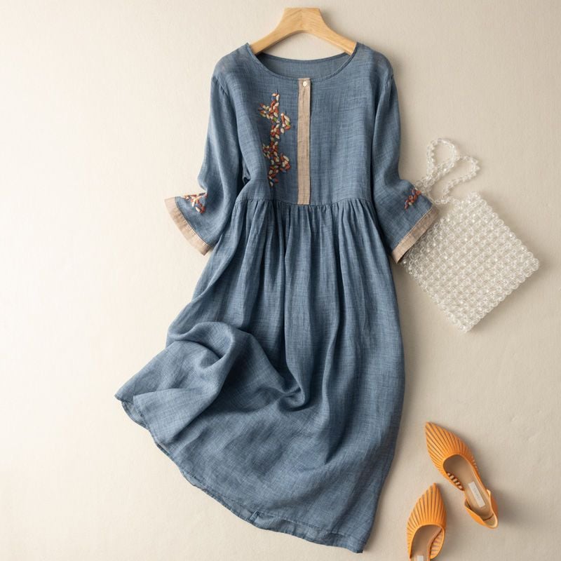 Side view of a relaxed embroidered midi dress styled casually with sandals in a blue pattern colorway