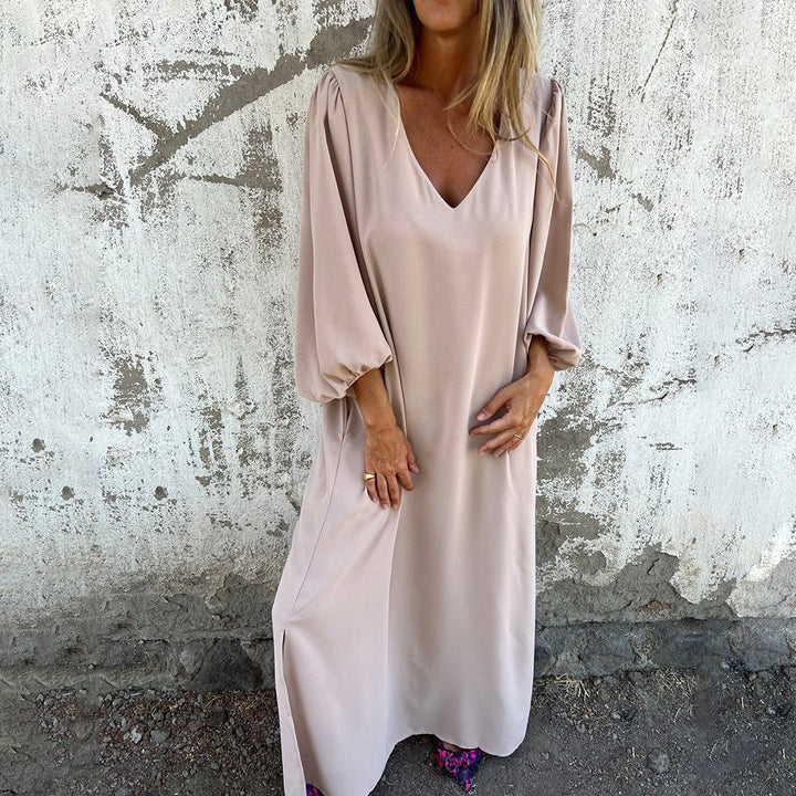 Woman wearing a flowing boho maxi dress with side slit and pockets in apricot
