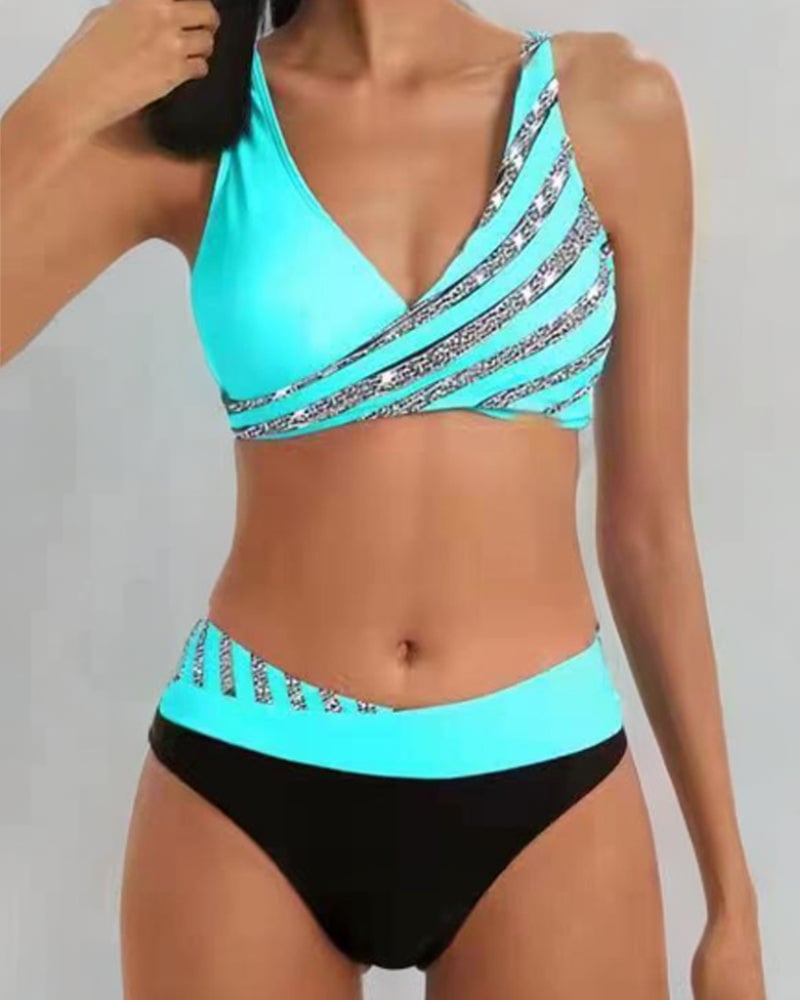 Woman wearing the Solange printed flattering bikini set in teal with a vibrant warm-toned print, standing on a sunny beach