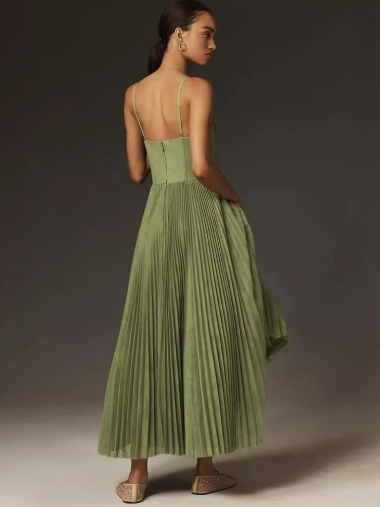 Model posing in an olive green maxi dress in a bright studio setting