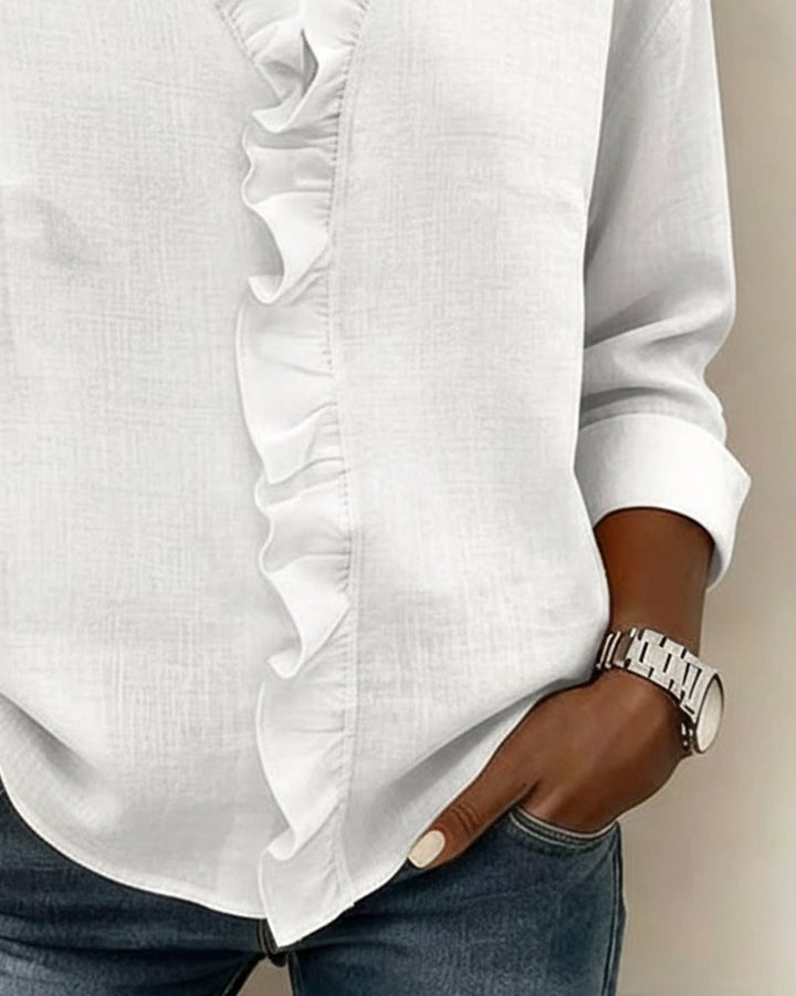 Close-up of the cuffed long sleeve and ruffle neckline on the Sophie blouse in white