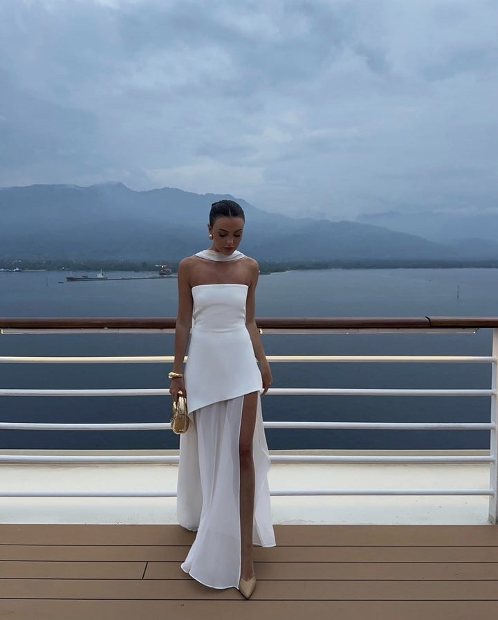 Side profile of woman in the Stella white asymmetric maxi dress highlighting the flowing high-low skirt