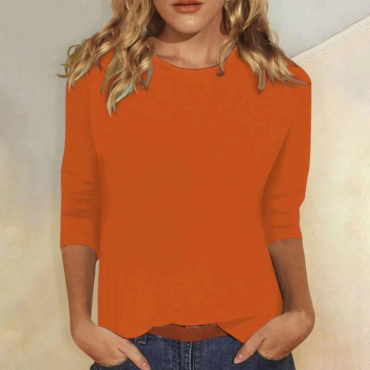 Woman in the Stella 3/4 sleeve top in orange smiling in a bright lifestyle setting