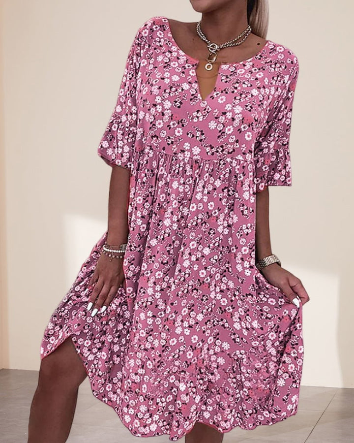 Woman wearing the Stella floral print V-neck midi dress in pink with short flutter sleeves and a smocked waist, styled for a casual summer day