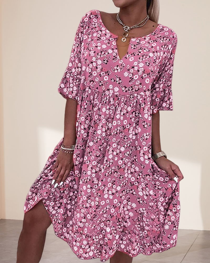 Woman wearing the Stella floral print V-neck midi dress in pink with short flutter sleeves and a smocked waist, styled for a casual summer day