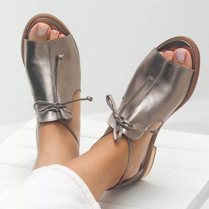 Stella metallic flat sandal with bow-tie side strap and open peep-toe in silver, front view