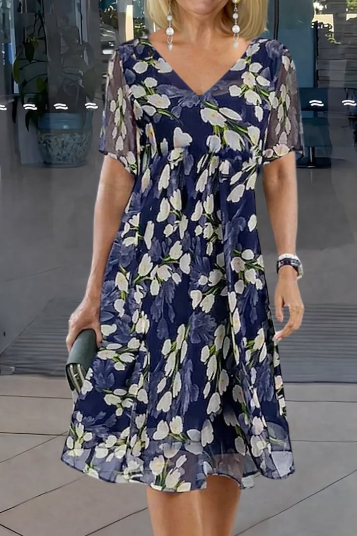 Model wearing a floral print double tunic dress in navy blue with a flowing A-line silhouette