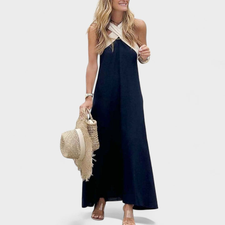 Woman wearing the cross-neck maxi dress in navy blue at an outdoor daytime gathering