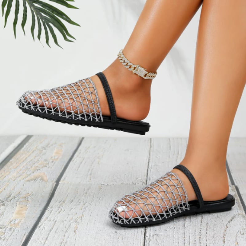 Model wearing Suzette sandals in black paired with a white linen dress outdoors