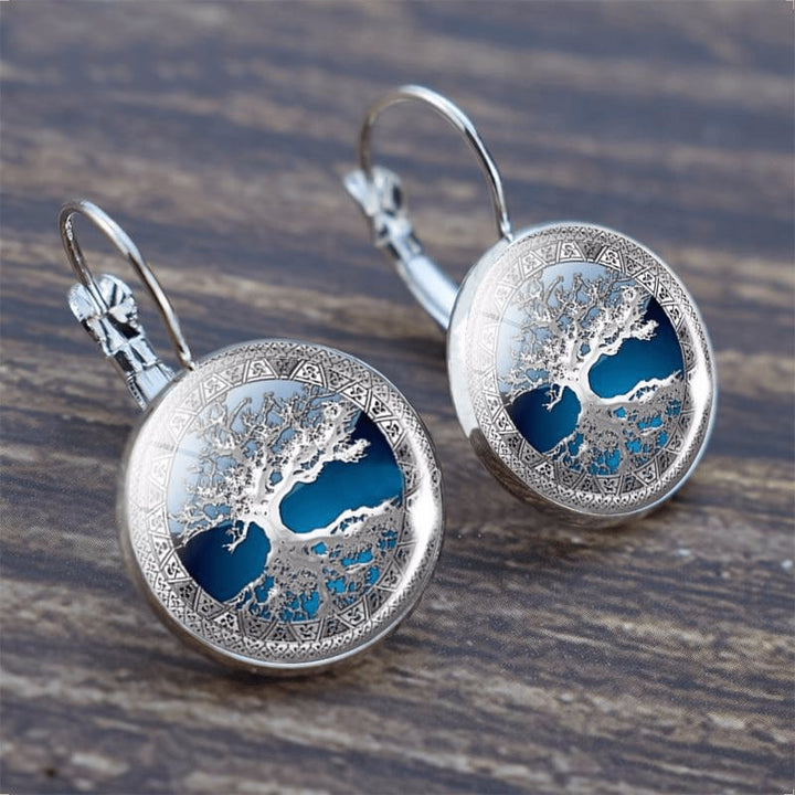 Silver tree of life hoop earrings with detailed branch and root motif on a white background