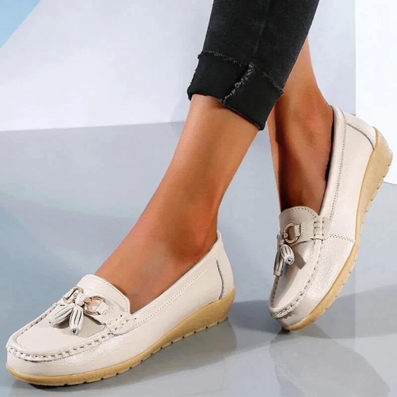 Talia tassel loafers in gold colorway on a neutral background, front three-quarter view