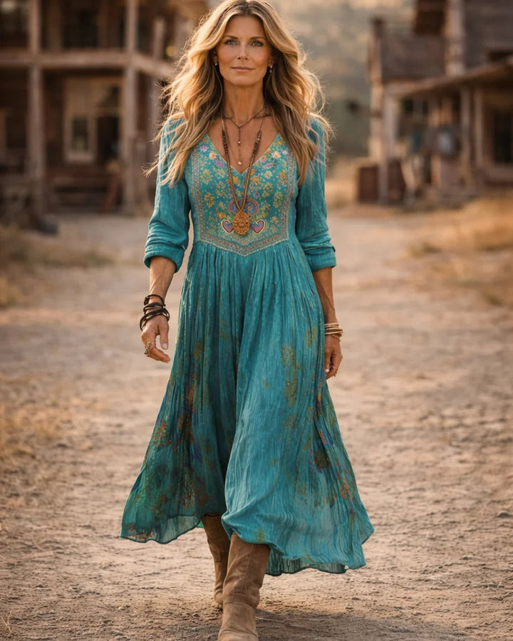 Close-up of intricate floral embroidery on the bodice of a teal long-sleeve maxi dress