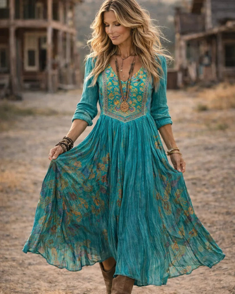 Back view of the Tamara teal embroidered V-neck maxi dress highlighting the long sleeves and skirt movement