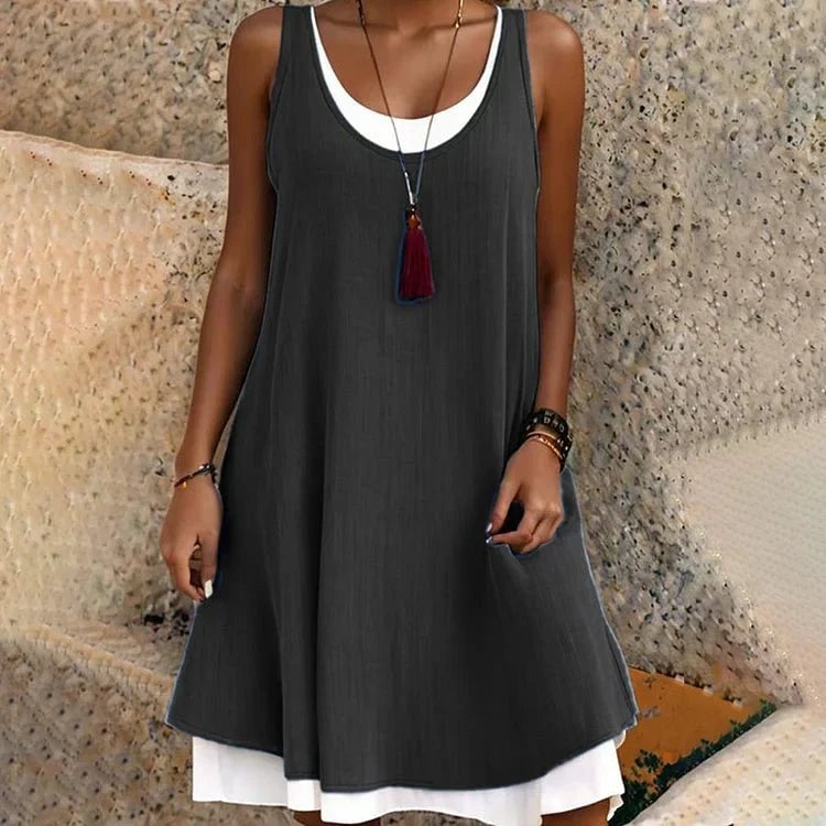 Woman wearing the Tessa sleeveless scoop neck layered mini dress in black with a flowy A-line silhouette and contrasting white underlayer