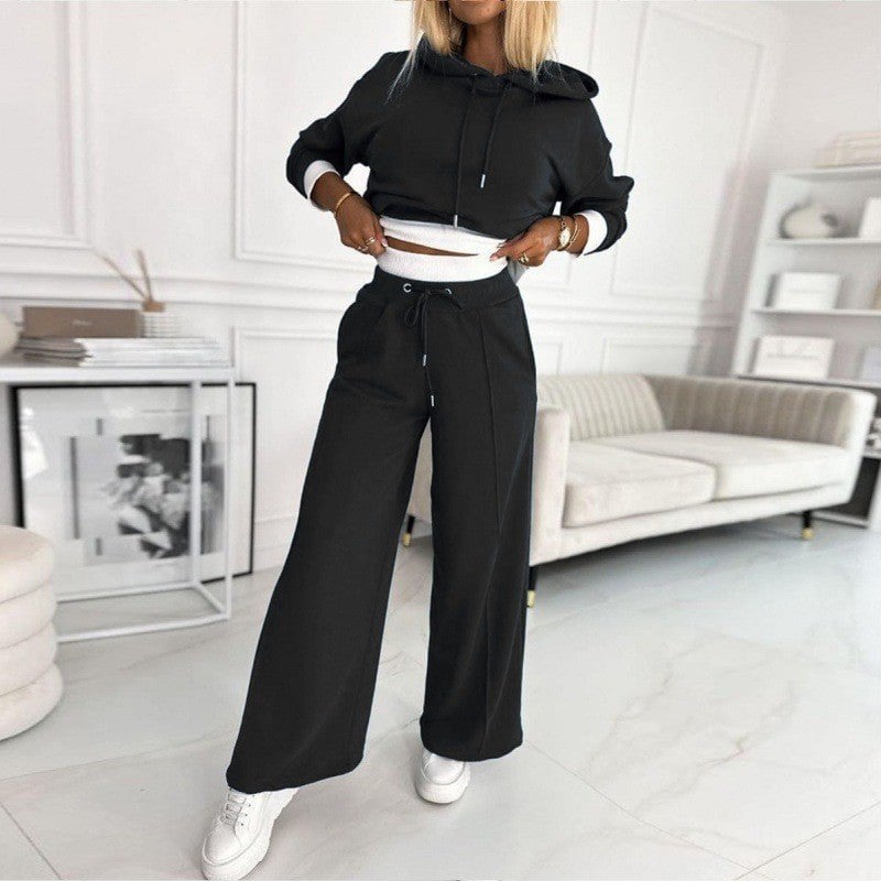 Woman in a grey two-piece hoodie and jogger set posed in a cozy home setting