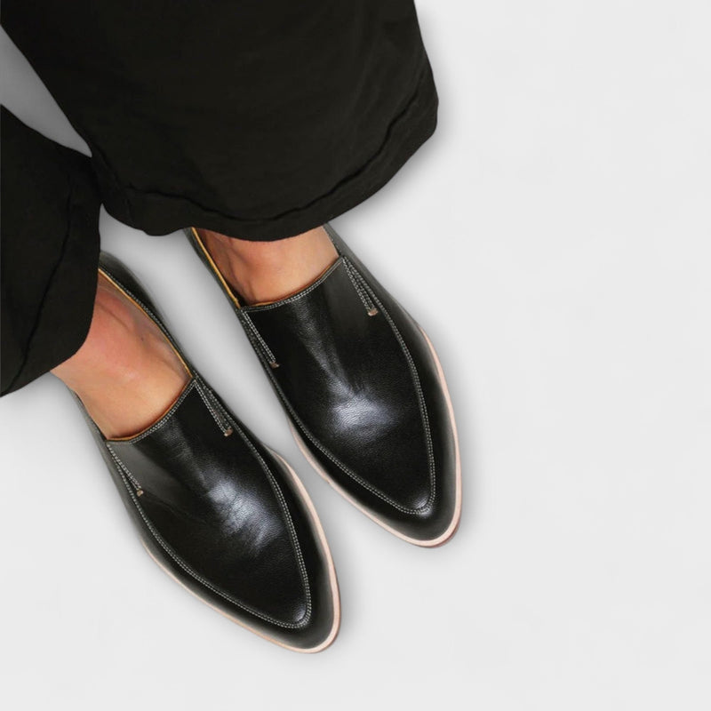 Close-up side profile of the Theodora black flat loafers highlighting the slip-on silhouette and sleek finish