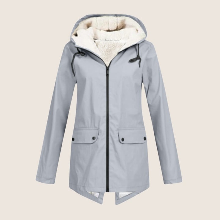 Woman in navy ThermaShell rain jacket walking outdoors in light rain, hood up