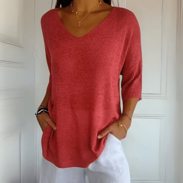 Woman wearing a soft V-neck knit top in red, styled casually with relaxed trousers