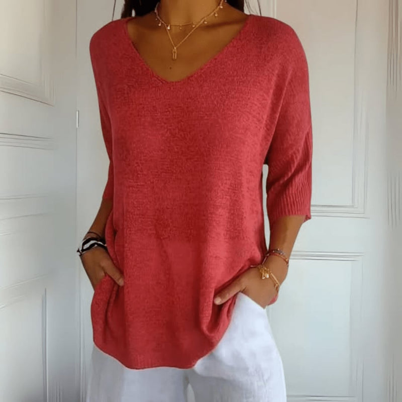 Woman wearing a soft V-neck knit top in red, styled casually with relaxed trousers