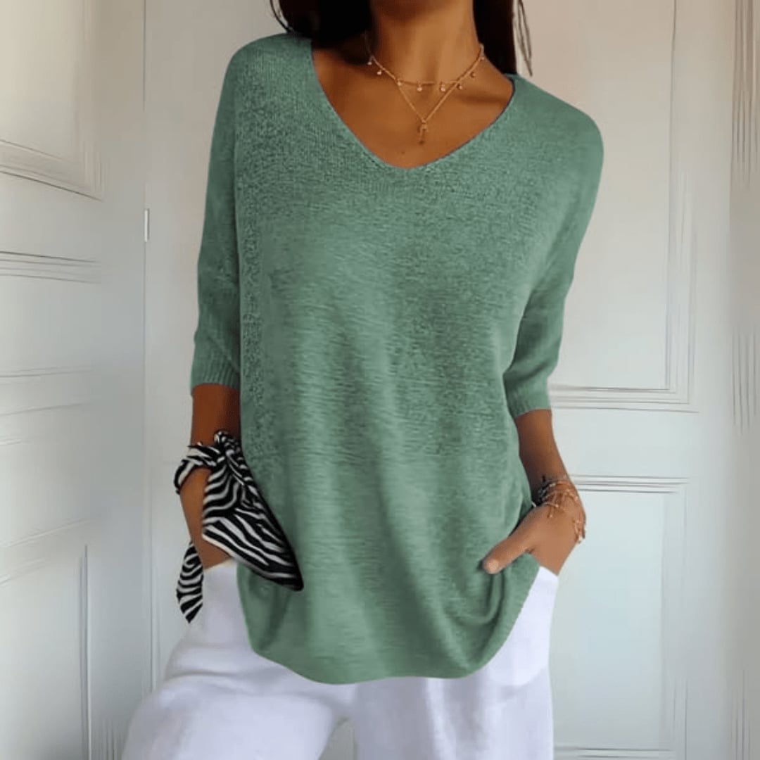 Woman wearing a V-neck knit top in apricot, layered under a light jacket for a polished look