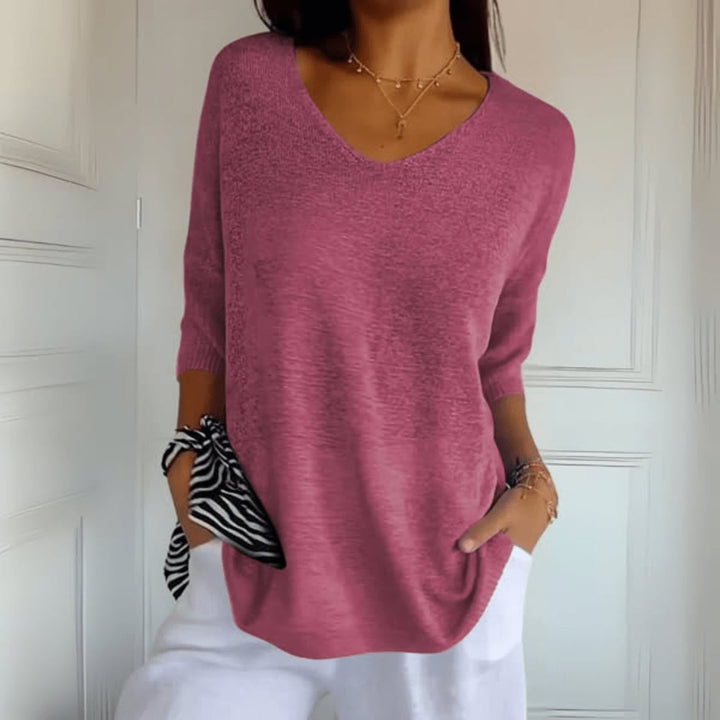 Side profile of woman in a soft knit V-neck top in light green, tucked into high-waisted jeans