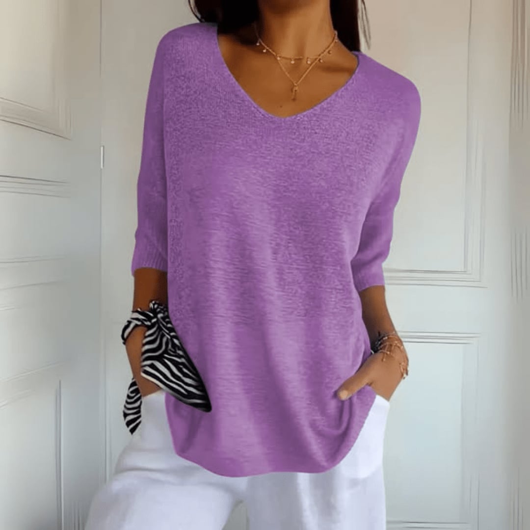 Woman in a pink V-neck knit top smiling, showcasing everyday casual style