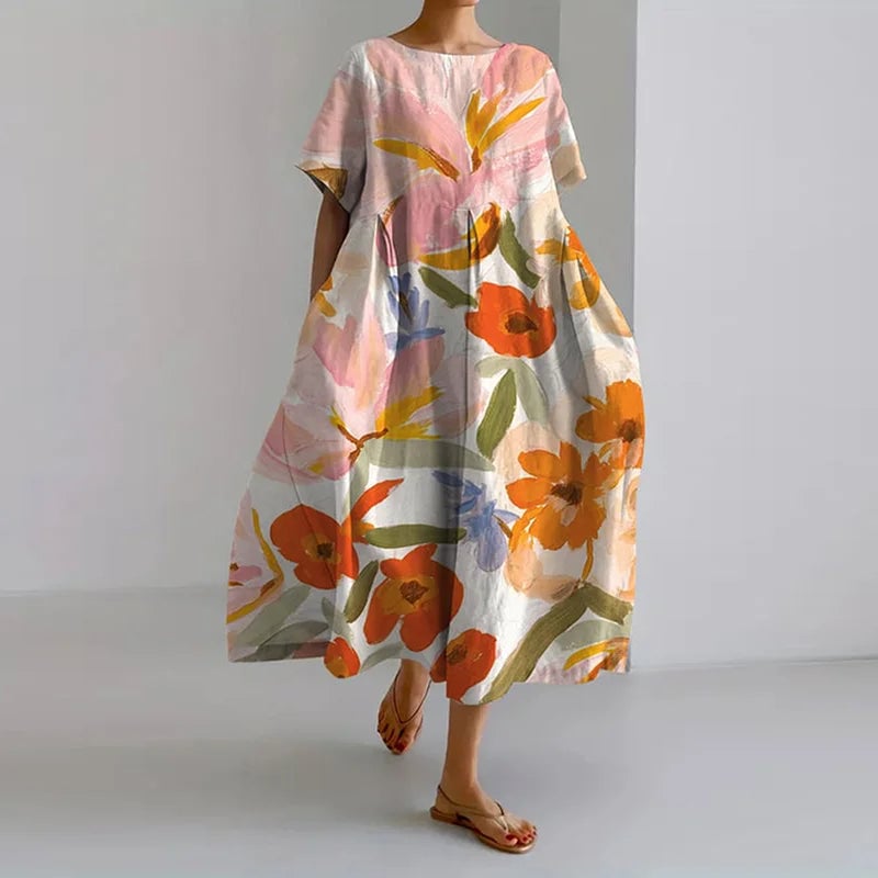 Woman wearing the Valentina floral summer dress in orange with a relaxed, flowing silhouette and pleated detailing