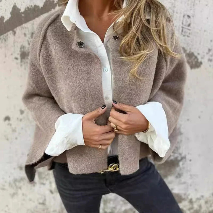 Side profile of a woman in a long elegant coat showing the clean tailored silhouette