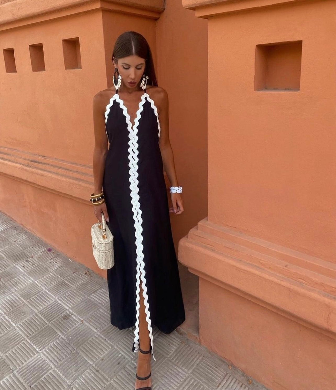 Woman wearing the Victoria black wrap dress with a flowing, figure-lengthening silhouette, styled for a wedding guest occasion