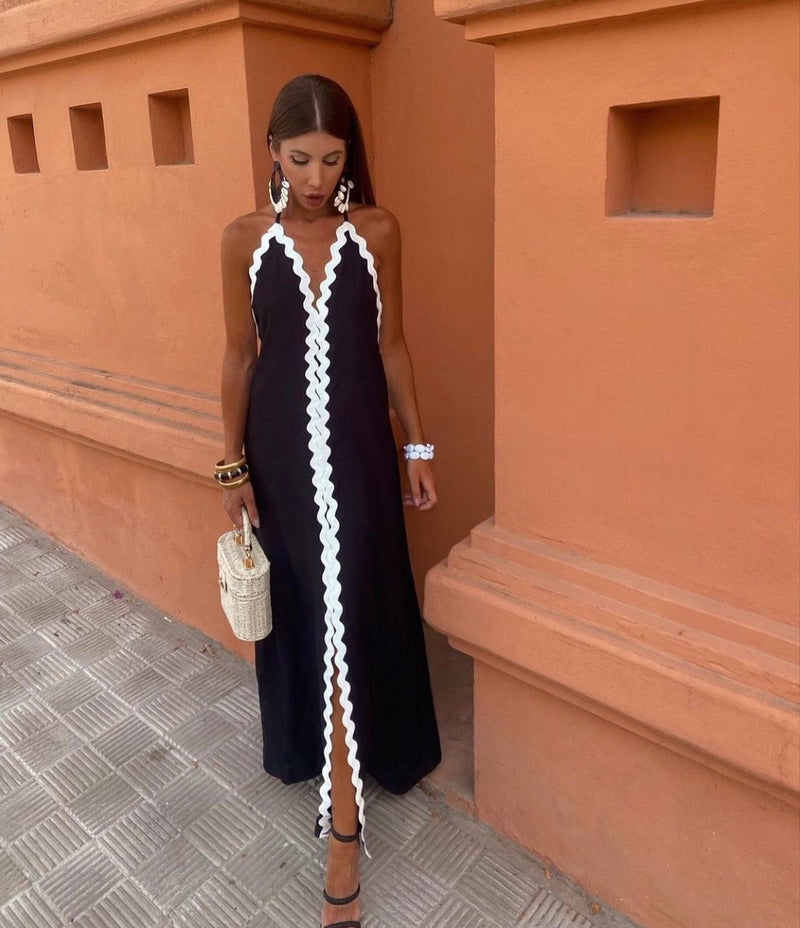 Woman wearing the Victoria black wrap dress with a flowing, figure-lengthening silhouette, styled for a wedding guest occasion