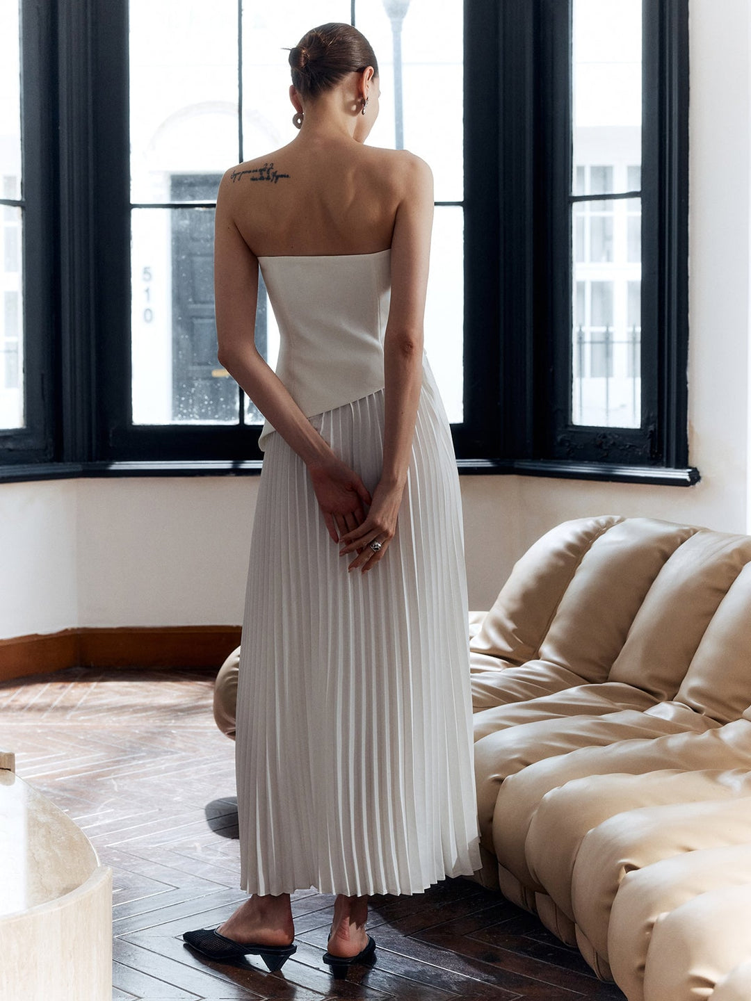Close-up of the asymmetric pleated skirt and side split on the Vienna maxi dress in white