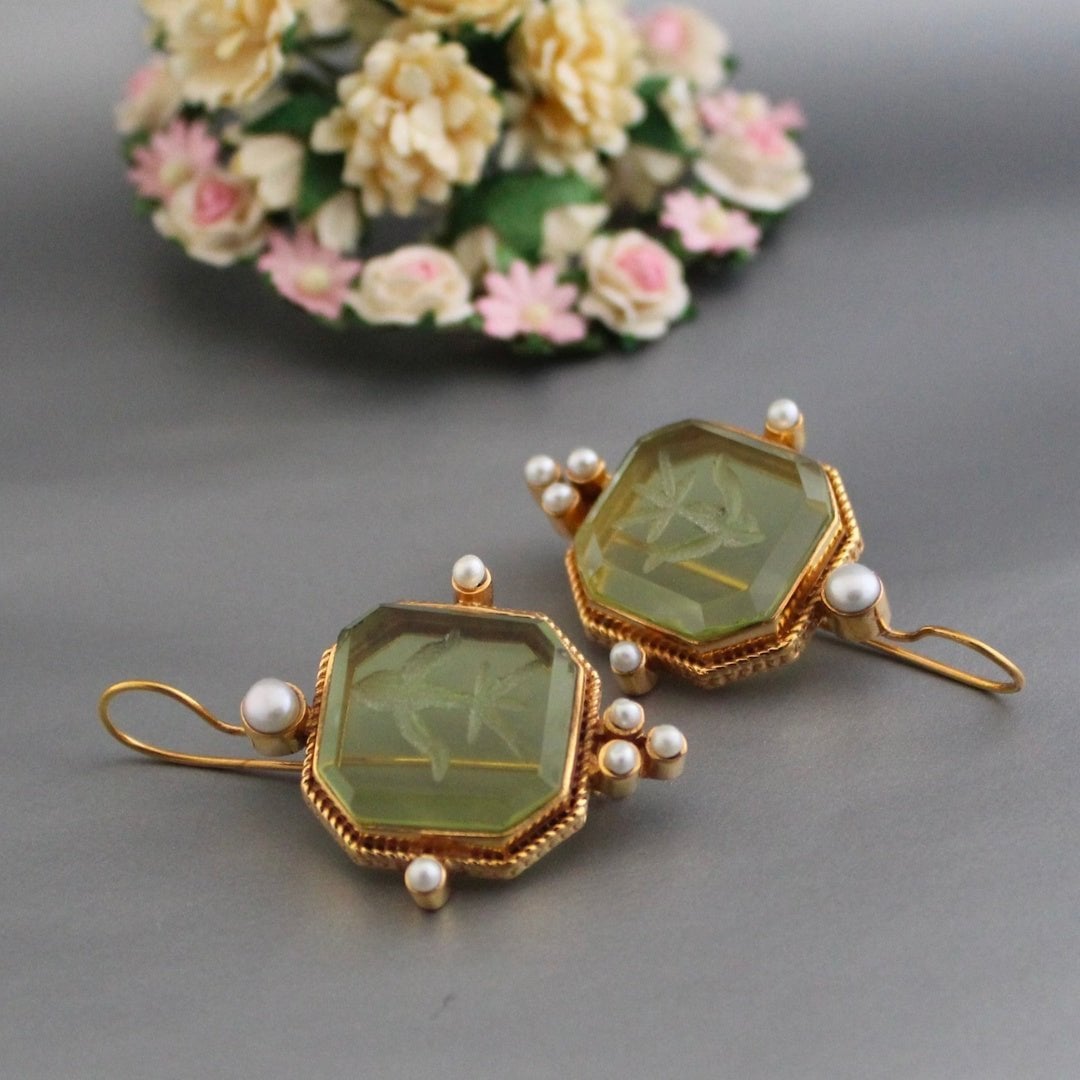 Vintage green and pearl drop earrings styled as a pair on a neutral background