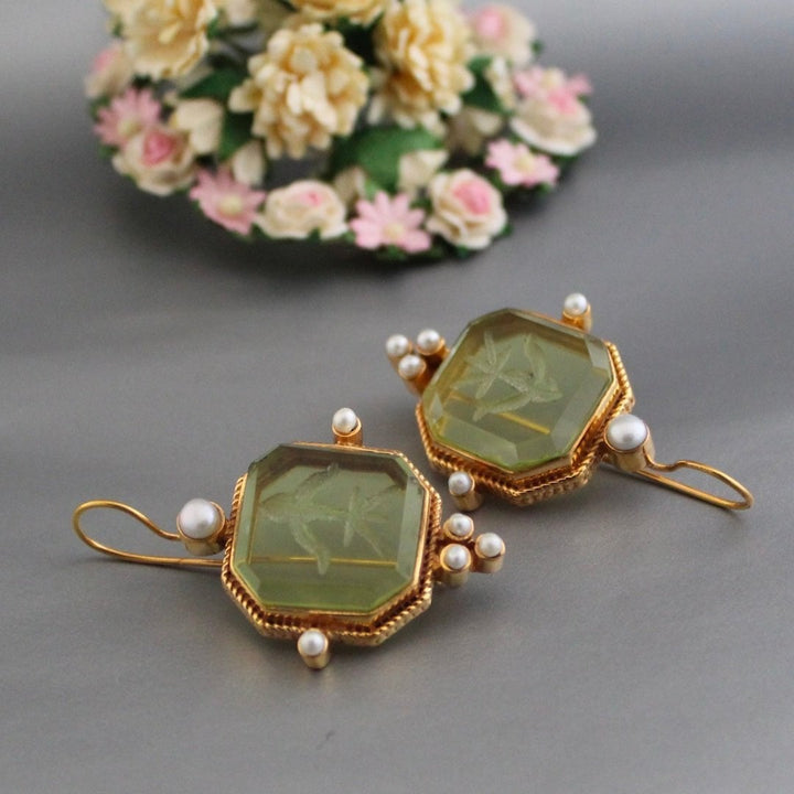Vintage green and pearl drop earrings styled as a pair on a neutral background