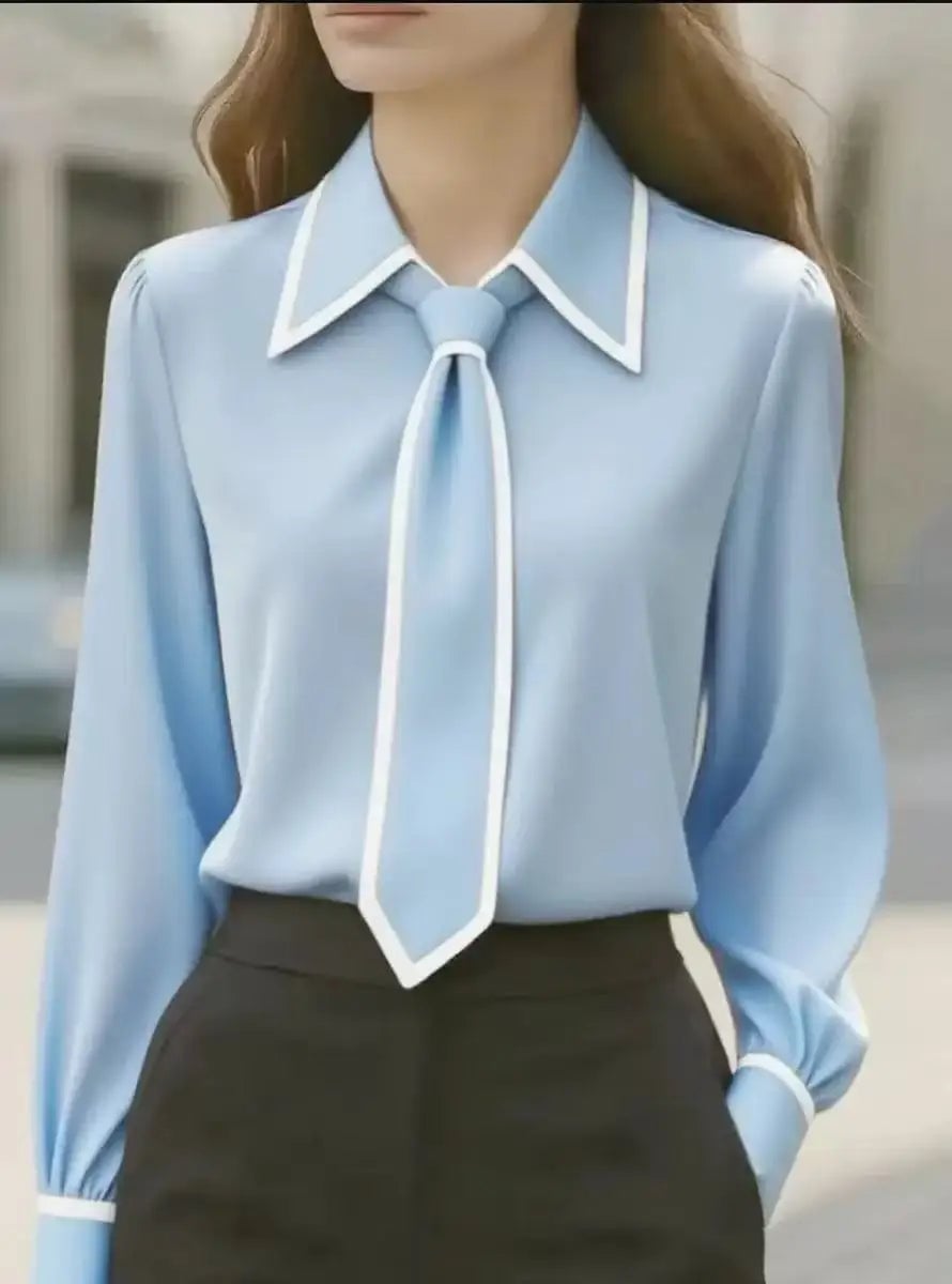 Model wearing the Vivian blouse in navy blue tucked into tailored trousers, styled for the office